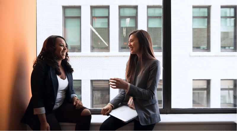 Two women smiling during workplace conversation
